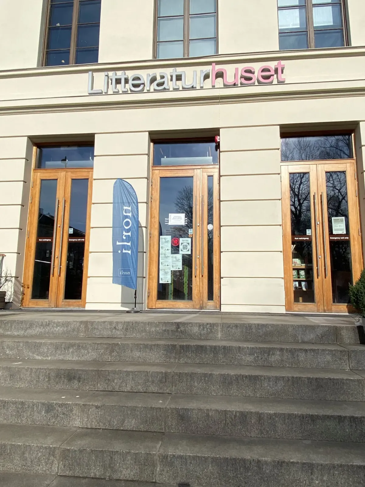 Litteraturhusets lyse, pussede fasade i tre etasjer med inskripsjonen Oslo Lærerskole over vinduene og Litteraturhuset-bannere ved inngangen. – bilde 5
