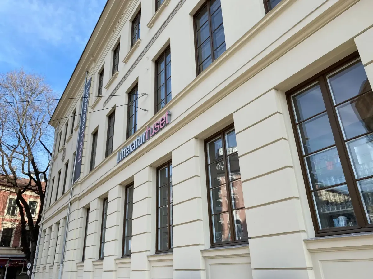 Litteraturhusets lyse, pussede fasade i tre etasjer med inskripsjonen Oslo Lærerskole over vinduene og Litteraturhuset-bannere ved inngangen. – bilde 6